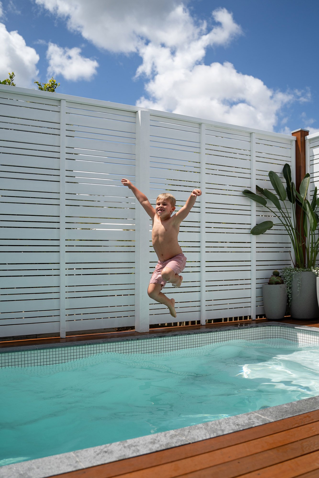 Young boy jumping into Aerial shot of 3.6m x 2.2m Plungie Studio Concrete Plunge Pool in Kona Coast